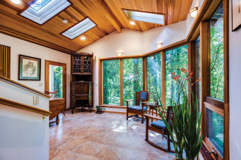 Interior of remodeled home showing wrap-around wall of windows, granite floors, and cedar ceiling with skylights