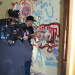 Photo of construction contractor being filmed as he begins demolition of an interior wall.