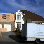 Photo of the exterior of the house with framing for addition above garage.