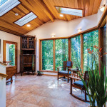 Large room with skylights and big windows that look out to forested area